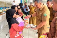 Sekda Konawe, Dr. Ferdinand Sapan (tengah), didampingi Camat Unaaha dan perwakilan Badan Gizi Nasional, menyerahkan paket makanan bergizi kepada ibu dan balita dalam launching Program MBG di Desa Ambakairi, Senin (4/8/2025).