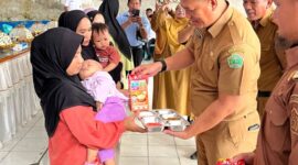 Sekda Konawe, Dr. Ferdinand Sapan (tengah), didampingi Camat Unaaha dan perwakilan Badan Gizi Nasional, menyerahkan paket makanan bergizi kepada ibu dan balita dalam launching Program MBG di Desa Ambakairi, Senin (4/8/2025).