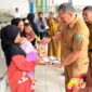 Sekda Konawe, Dr. Ferdinand Sapan (tengah), didampingi Camat Unaaha dan perwakilan Badan Gizi Nasional, menyerahkan paket makanan bergizi kepada ibu dan balita dalam launching Program MBG di Desa Ambakairi, Senin (4/8/2025).