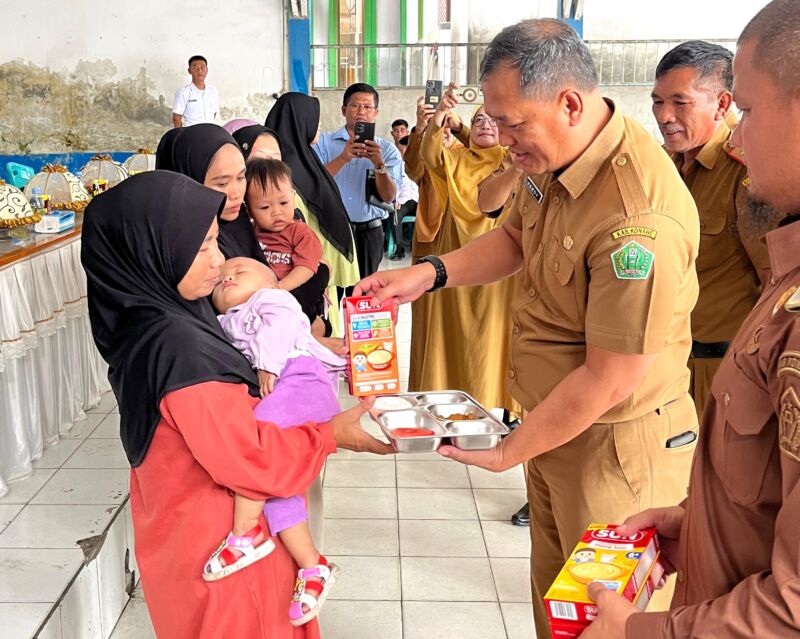Sekda Konawe, Dr. Ferdinand Sapan (tengah), didampingi Camat Unaaha dan perwakilan Badan Gizi Nasional, menyerahkan paket makanan bergizi kepada ibu dan balita dalam launching Program MBG di Desa Ambakairi, Senin (4/8/2025).