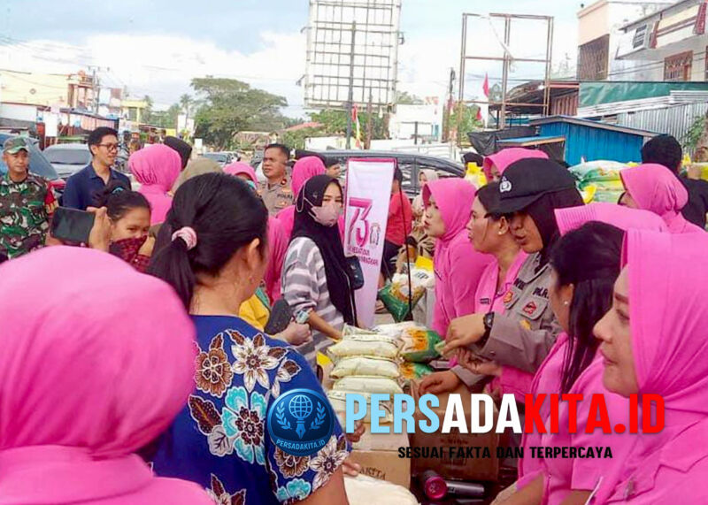 Petugas Polres Konawe dan ibu-ibu Bhayangkari aktif membagikan beras kepada warga saat pasar murah di depan Pasar Wawotobi, Kamis (15/8/2025). Sebanyak 4 ton beras SPHP dijual Rp58.000/5 kg, lebih murah dari harga pasar.