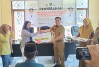 Asisten I Sekretariat Daerah Kabupaten Konawe, Marjuni Ma'mir, menyerahkan secara simbolis dana hibah program pemberdayaan UMKM kepada perwakilan penerima di Kantor Dinas Koperasi dan UMKM, Selasa (23/12/2025).