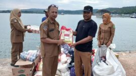 Kepala Bidang Perlindungan dan Jaminan Sosial Dinsos Konawe, Amos Demi, S.Si., menyerahkan bantuan pokok kepada perwakilan warga terdampak didampingi Kepala Desa Saponda Laut.