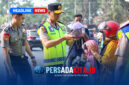 Kapolda Sultra Irjen Pol. Dr. Himawan Bayu Aji, S.H., S.I.K., M.H., memakaikan helm kepada seorang anak yang dibonceng sepeda motor, didampingi personel kepolisian lainnya
