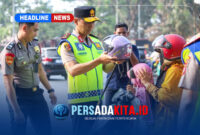 Kapolda Sultra Irjen Pol. Dr. Himawan Bayu Aji, S.H., S.I.K., M.H., memakaikan helm kepada seorang anak yang dibonceng sepeda motor, didampingi personel kepolisian lainnya