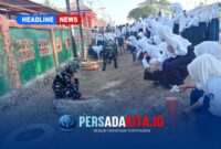 Personel Satgas TMMD 130 Kodim 1416/Muna dan siswa-siswi SMP 1 Kabawo bergotong royong membersihkan rumput dan sampah di pinggir jalan depan sekolah, Kamis (22/10/2026).